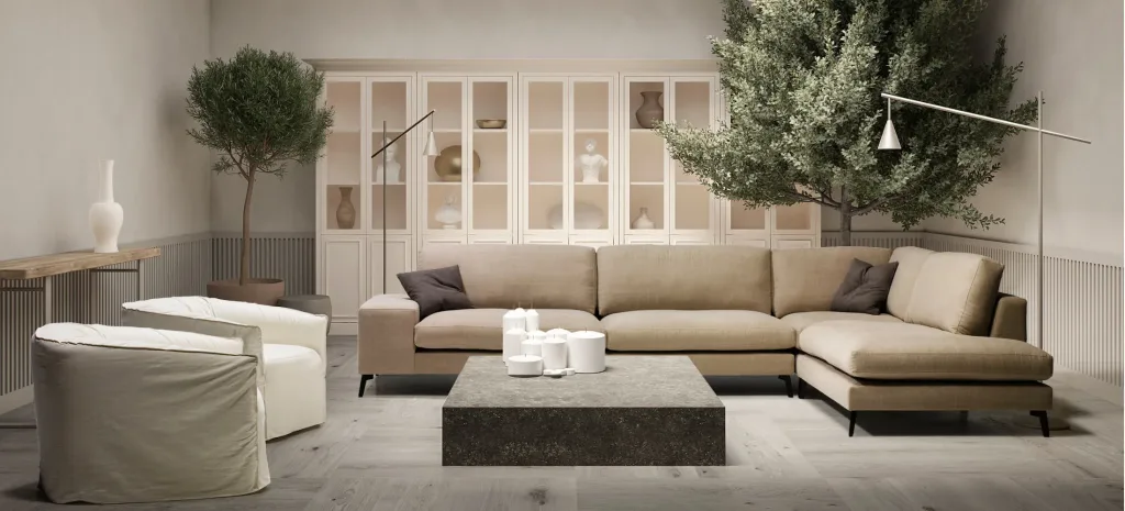Salón con sofá rinconera Zow en beige, mesa de centro baja gris, dos butacas blancas y olivos