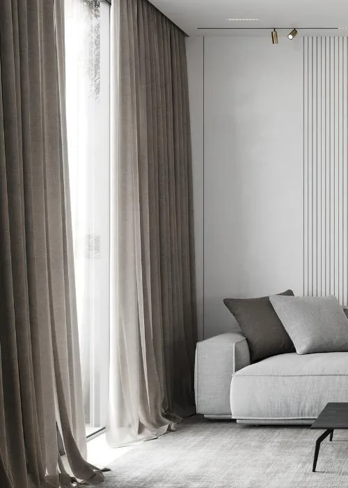 Cortinas largas en gris pardo junto a un ventanal, con un sofá blanco y cojines grises