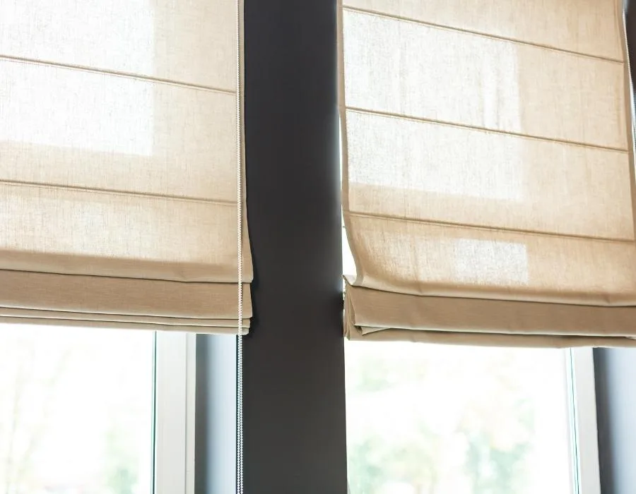 Detalle de dos estores paqueto beige con sus pliegues horizontales, a contraluz ante un ventanal