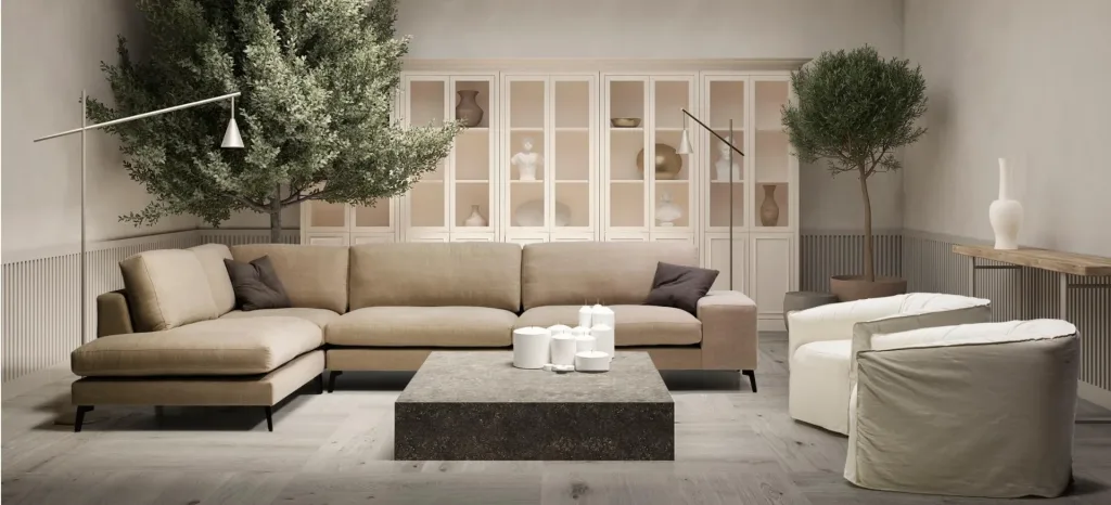 Salón con sofá Zow rinconera en beige, mesa de centro oscura con velas, dos butacas blancas y árboles en maceta