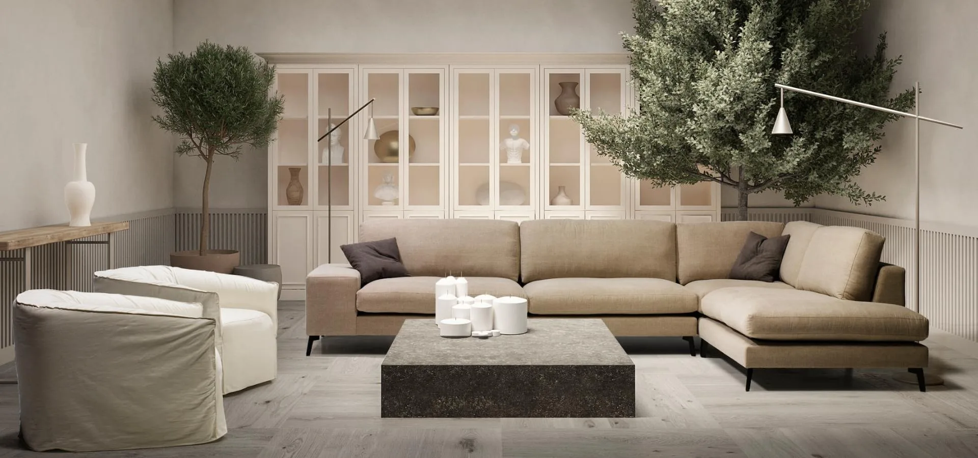 Sofá Zow en rinconera beige con cojines grises, en un salón con mesa de centro oscura, butacas blancas y árboles en maceta