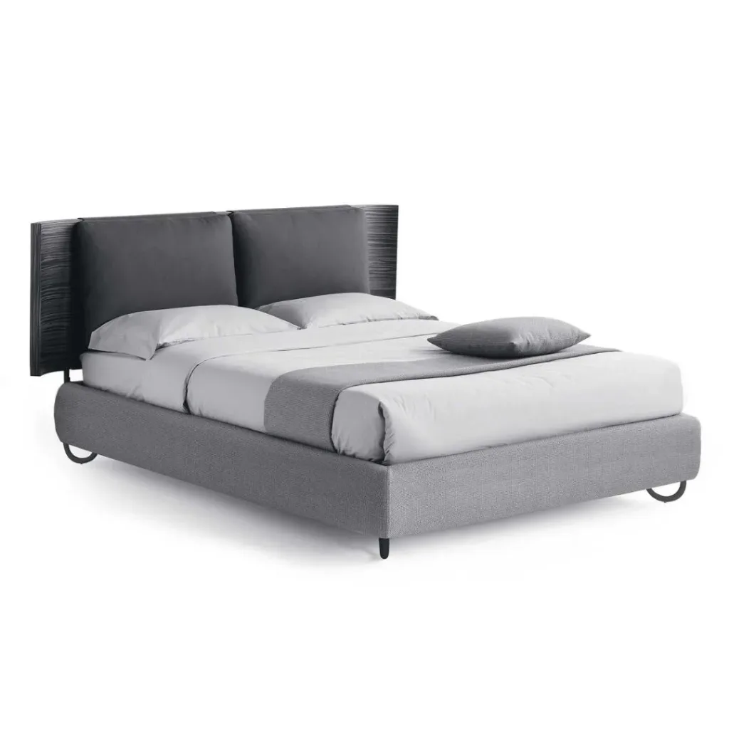 Cama con base tapizada gris y cabecero oscuro con dos cojines rectangulares en gris antracita