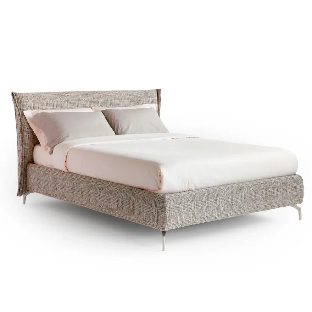 Cama con cabecero de alas y base tapizados en gris jaspeado, patas metálicas y ropa rosa claro