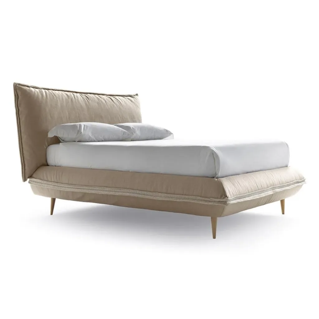 Cama tapizada en beige arena con cabecero acolchado ligeramente inclinado y patas de madera clara