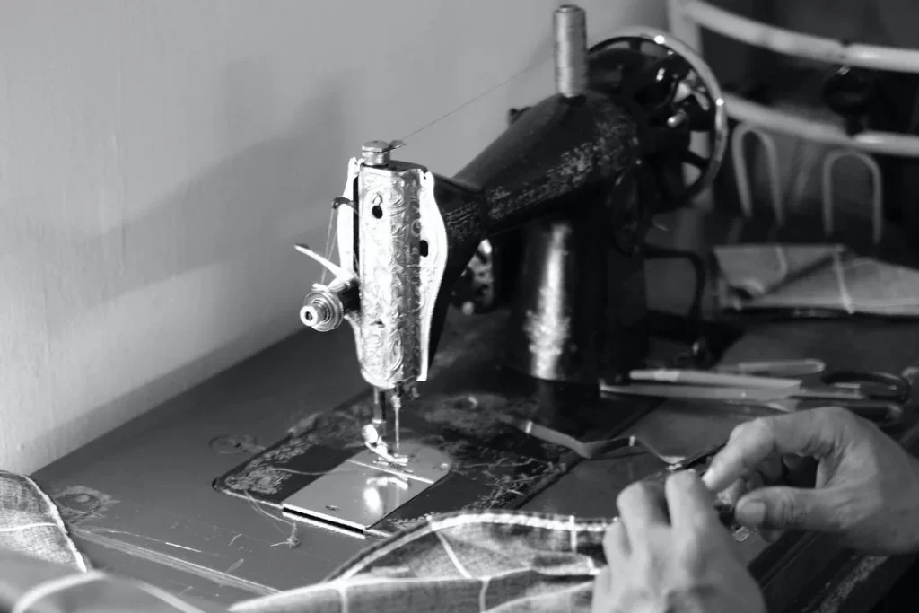 Manos cosiendo una tela en una máquina de coser antigua, en blanco y negro